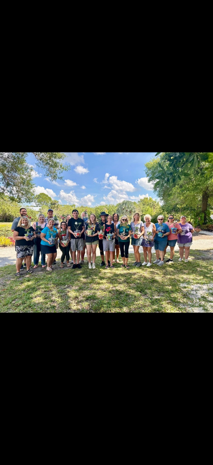 A group of class participants holding their potted desert roses in the gardens